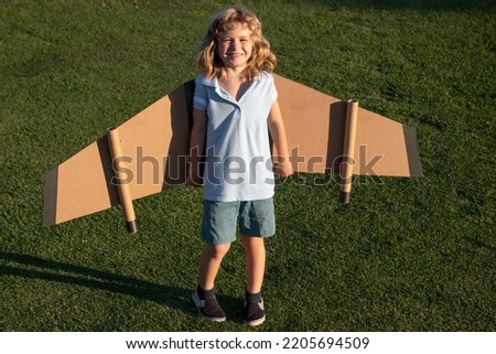 Cute dreamer boy playing with a cardboard airplane. Childhood. Fantasy, imagination.