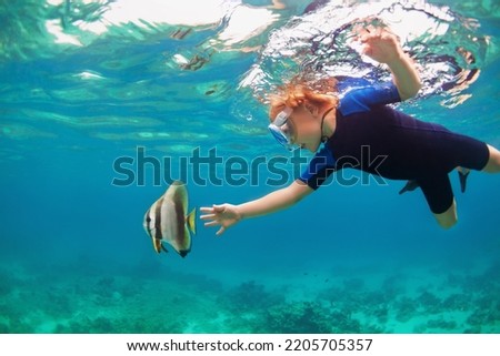 Happy family - active kid in snorkeling mask dive underwater, see tropical fishes in coral reef sea pool. Travel adventure, swimming activity on summer beach vacation with child. Royalty-Free Stock Photo #2205705357