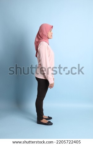 The senior southeast Asian woman with hijab standing on the blue background
