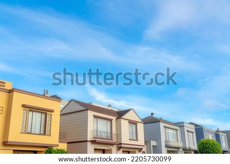 Suburbs houses with colorful exterior against the sky in San Francisco, California. There are houses in a row with picture windows and railings.