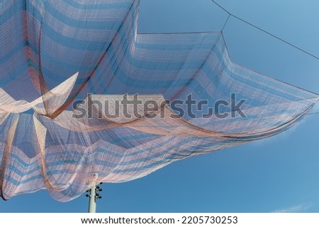 Extremely large shade cloth, pink with blue stripes, blue sky creative copy space, horizontal aspect