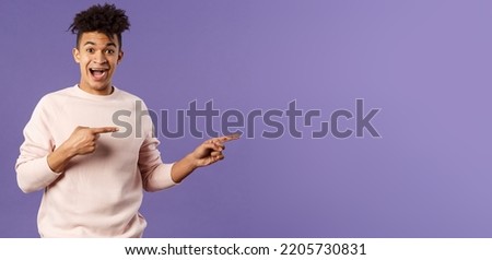 Portrait of enthusiastic lively hipster male 25s, pointing fingers right inviting join courses, sign up for awesome deal, best delivery service or online shop, look amused and happy camera