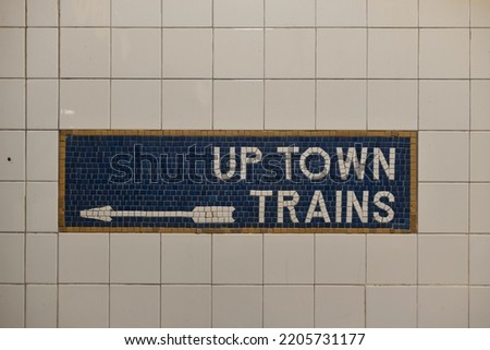 Tiled New York City subway train sign with arrow pointing direction.