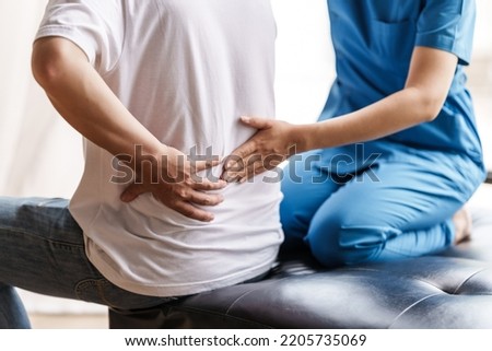Physical therapist is examining the injured arm, waist and neck muscles of an athletic male patient. Royalty-Free Stock Photo #2205735069