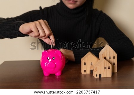 Household savings and finances, Smiling Woman putting coin in piggy bank. Saving money concept