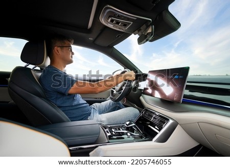 An Asian man drives from town to go on a summer vacation. Happy Asian man in casual wear and beautiful new driving glasses. Royalty-Free Stock Photo #2205746055