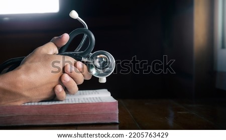 Hands holding stethoscope and the Bible and pray for healing, concept for treatment, science and religion, close up hands praying, with copy space , space for text. Royalty-Free Stock Photo #2205763429
