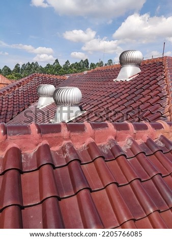 the roof of a house with roof fans that serve to enhance air circulation and to reduce heat inside the house