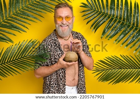 Photo portrait of nice grandpa coco cocktail palm branches resort dressed stylish leopard print look isolated on yellow color background