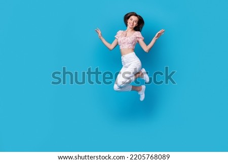 Full length photo of good mood lady dressed trendy clothes rejoice cool purchase jumping empty space isolated on blue background