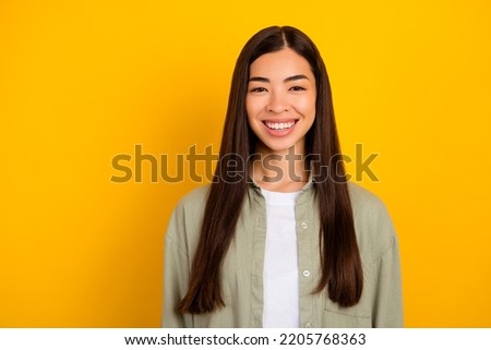 Portrait of young lovely cheerful female with long strong brown hair after salon treatment isolated on yellow color background