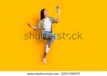 Full size portrait of excited crazy lady hold telephone make selfie have good mood isolated on yellow color background