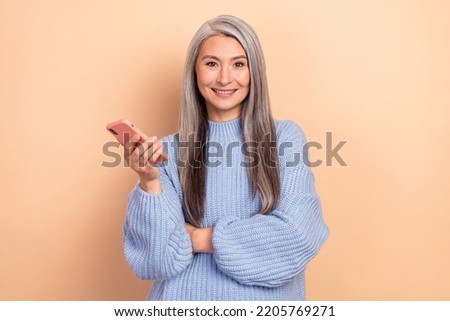 Photo of shiny adorable retired lady wear blue sweater typing modern device isolated beige color background