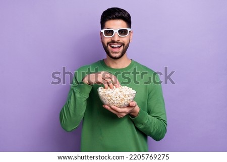 Photo of impressed open mouth guy dressed green pullover eating popcorn hand look astonished at camera isolated on purple color background