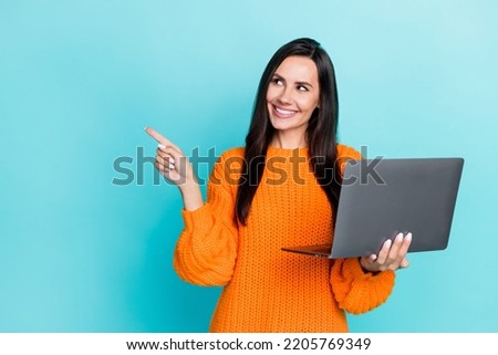 Photo of gorgeous lovely girl straight hairdo dressed orange sweater indicating empty space hold laptop isolated on teal color background