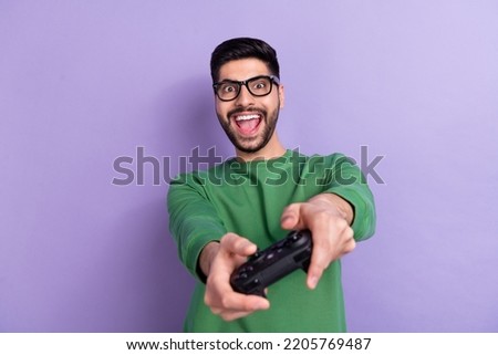 Photo of positive cheerful good mood gamer wear green long sleeve impressed playstation have fun isolated on purple color background