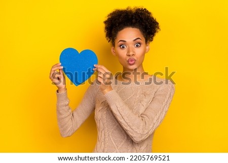 Photo of flirt young brunette lady hold heart blow kiss wear sweater isolated on yellow color background