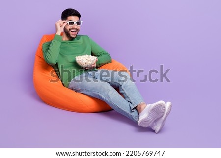 Full size photo of young excited hispanic man watching movie eat popcorn dressed trendy green outfit isolated on violet color background
