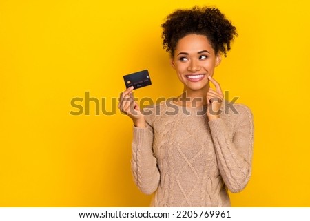 Photo of think millennial brunette lady hold card look promotion wear sweater isolated on yellow color background
