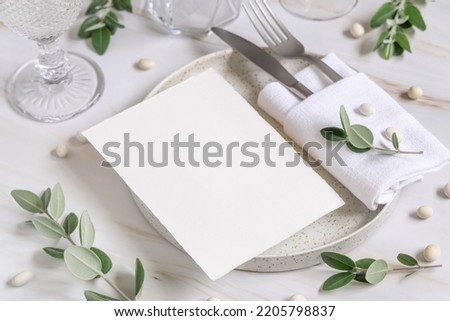 Elegant Table setting with a blank card decorated with eucalyptus branches close up, Wedding Mockup. Romantic table with paper invitation card. Close to nature and simplicity concepts