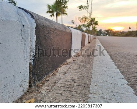 close up of black and white striped concrete barriers on the asphalt road. cement blocking.traffic equipment. horizontal stripes for traffic signs. highway concrete barriers on the road