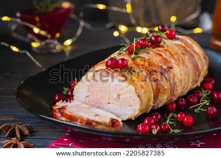 Cold appetizer, whole baked turkey and minced meat roll wrapped in bacon, on a black plate on a dark wooden background. Recipes for Thanksgiving, Christmas.