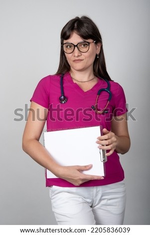 Medical concept of a beautiful female doctor with a stethoscope, waist up. Medical student. A hospital worker looks at the camera, studio, gray background.