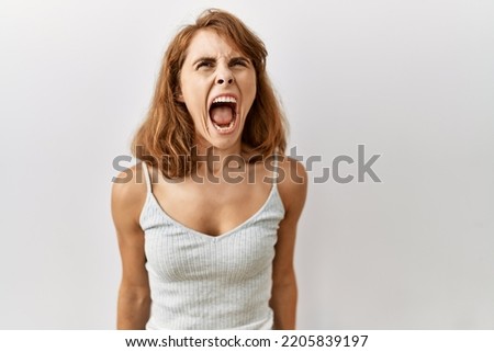 Beautiful caucasian woman standing over isolated background angry and mad screaming frustrated and furious, shouting with anger. rage and aggressive concept.  Royalty-Free Stock Photo #2205839197