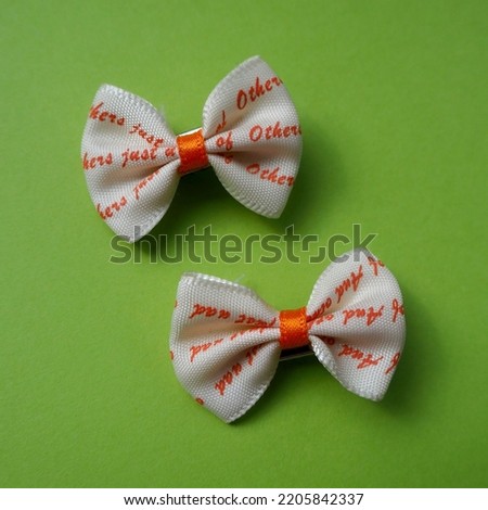 two beige and orange hair bows lie on a green background. view from above. accessories