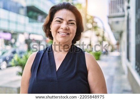 Middle age hispanic woman smiling happy and confident outdoors on a sunny day Royalty-Free Stock Photo #2205848975