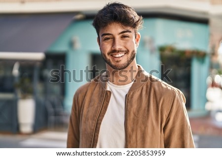Young hispanic man smiling confident standing at street Royalty-Free Stock Photo #2205853959