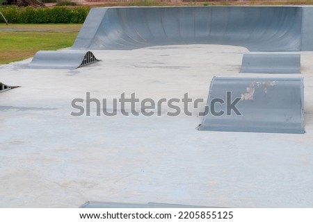 outdoor skatepark with blue sky and grey concrete