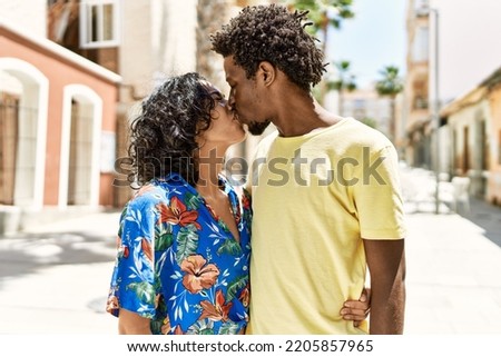 Young interracial couple kissing and hugging at the city.