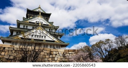 Landscape photo of Osaka Castle in late spring, where there are still some cherry blossoms still in bloom.