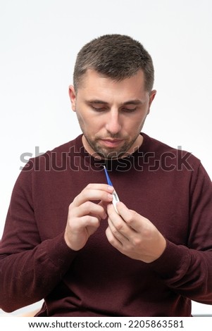 Sick man holding thermometer, healthcare and treatment, man checking body temperature.