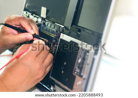 A repair technician is using a meter to measure the malfunction of the notebook computer's electronics. Electronic equipment and deterioration and find a way to repair