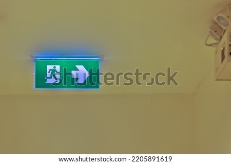 Green emergency exit sign showing the way to escape. Fire exit in the building.	