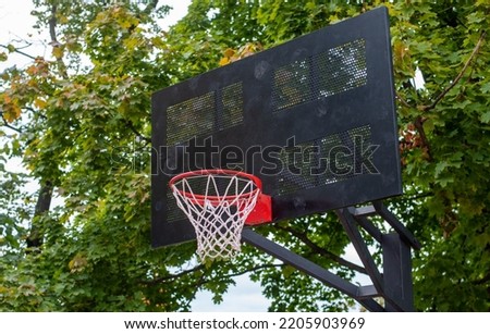 A red hoop on a black metal backboard on a basketball court in a park.