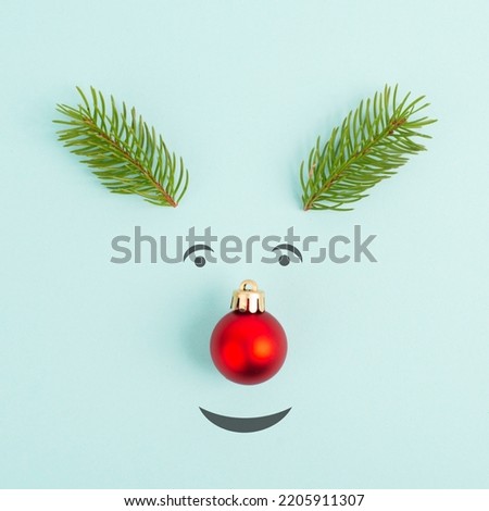 Face of a reindeer with a red bauble nose, fir antlers and friendly eyes, merry christmas greeting card 