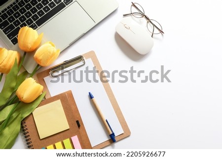 Flat lay woman's office desk. female workspace with laptop, glasses , tulip flower , notepad on white background.