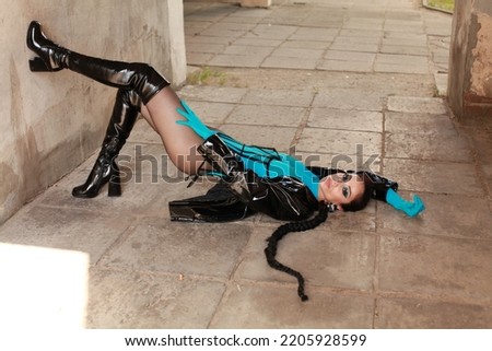 Portrait of brunette wearing leather coat, blue body suit, gloves. Stylish female in bdsm outfit posing on urban setting outside. fashion latex details. Modern street style youth subcultures concept
 Royalty-Free Stock Photo #2205928599