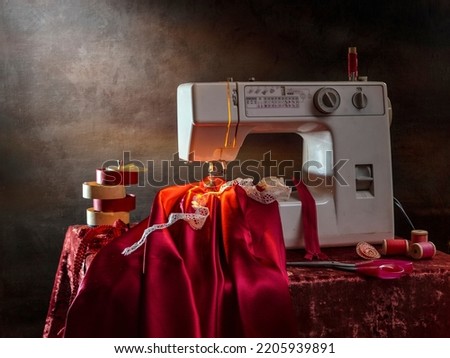 Still life with a sewing machine and a red cloth on a dark background.