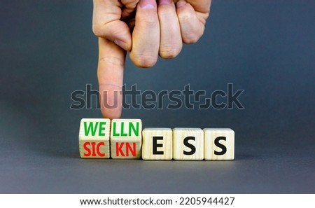 Sickness or wellness symbol. Concept words Sickness or Wellness on wooden cubes. Businessman hand. Beautiful grey table grey background. Business sickness or wellness concept. Copy space.