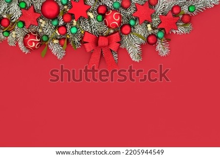 Christmas snow fir mistletoe bow and bauble background border. Traditional nature composition with tree decorations for festive Xmas holiday season on red.
