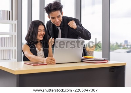 Two business people working together with smile on face using laptop at the office
