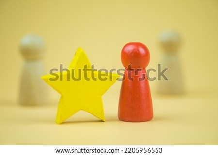 A wooden red doll that different and standing out from the competitor and yellow star. Concept of leader. The concept of raising the level of individuals in the organization