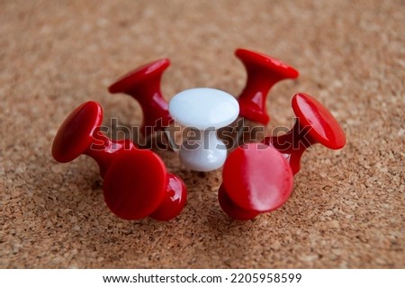 White push pin surrounded by red push pins. Harassment and discrimination concept.