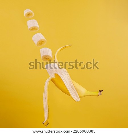 Floating half peeled banana and slices on yellow background