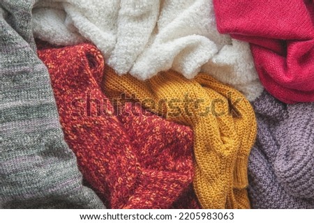 Autumn and winter background with folded in stack of knitted colourful sweaters
