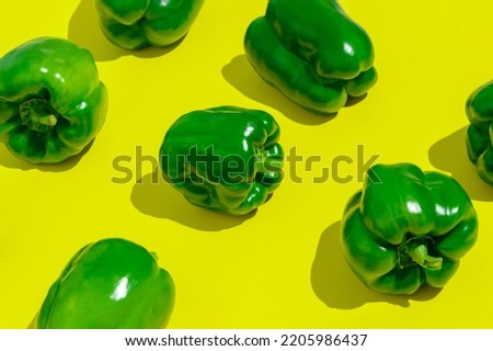 green bell pepper on a yellow backdrop with hard shadows and light